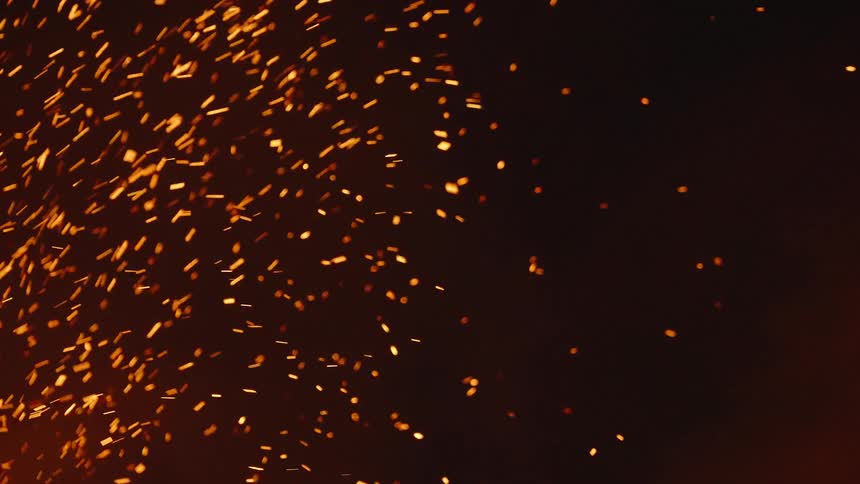 Close up of embers flying across the dark sky at night
