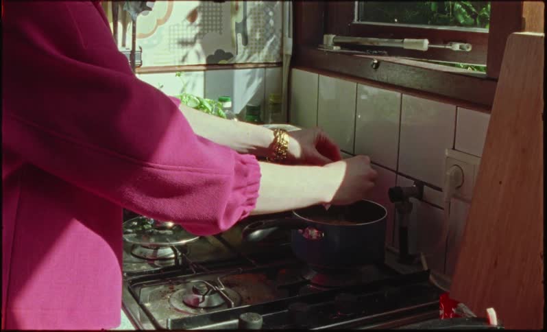 A woman prepares food in a pot stirring it
