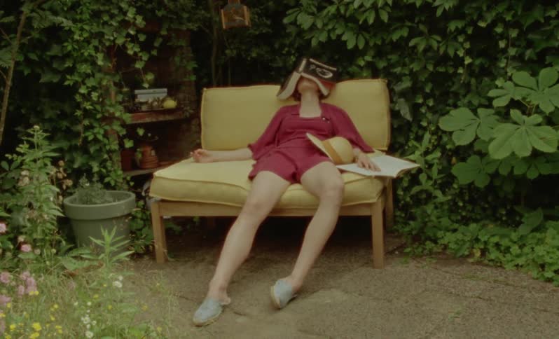 A woman asleep outside with a book over her face