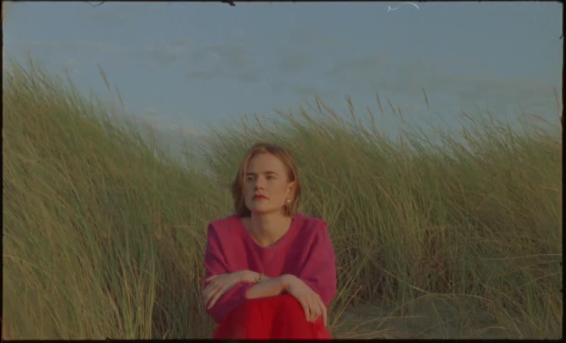 Woman sitting in a wheat field on a very windy day