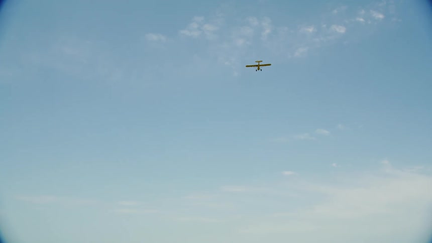 Small yellow plane flying over the blue sky