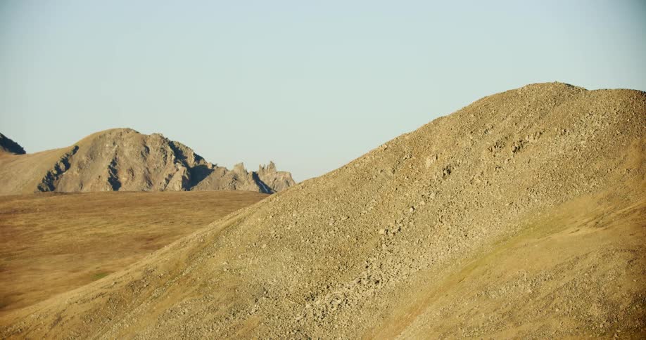 Low hills separate mountains on a sunny day