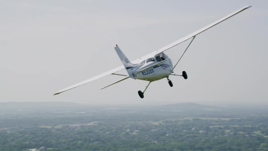 A small airplane soars above the city on a mostly clear day