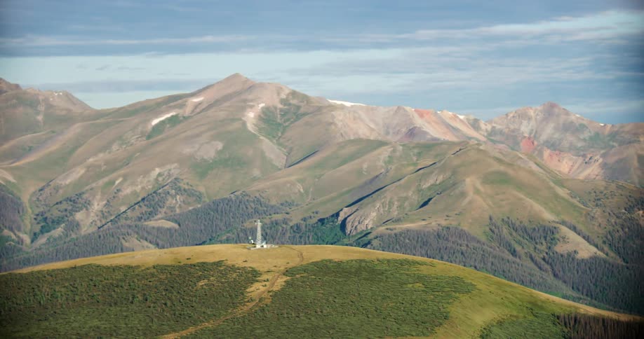 Aerial panorama of hills and mountains and greenish covered forests on a blue sky day