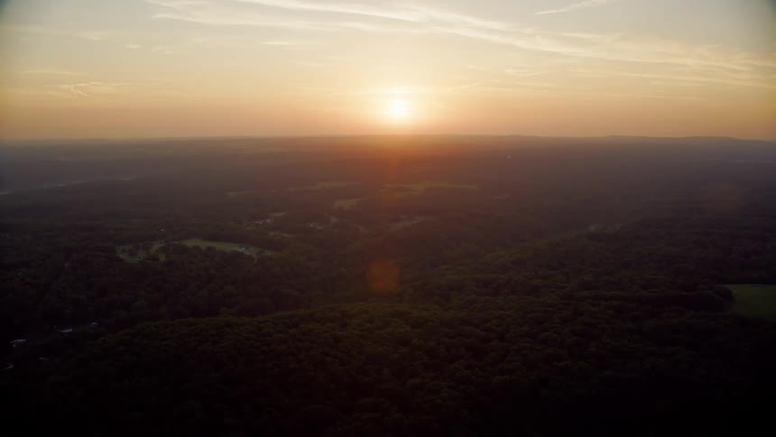 Aerial landscape of hills covered with forests and the sunset on the horizon