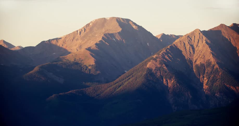 Forest covers the lower slopes of mountains in range