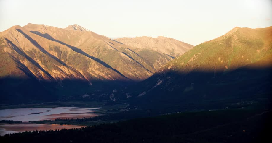 The top halves of the mountains are bathed in sunlight while the lake is in the shadows