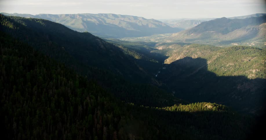 Mountains cast large shadows on the lower mountains below them on a bright day