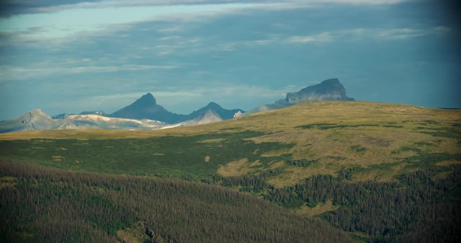 Aerial landscape of greenish hills and mountains with forests in a blue sky with clouds