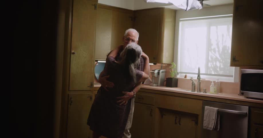 Older couple dancing and kissing in the kitchen