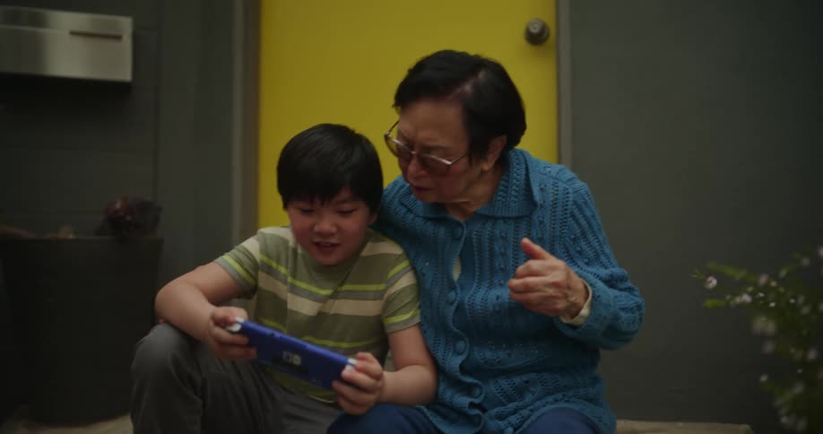 A grandmother high fives her grandson after winning on a video game