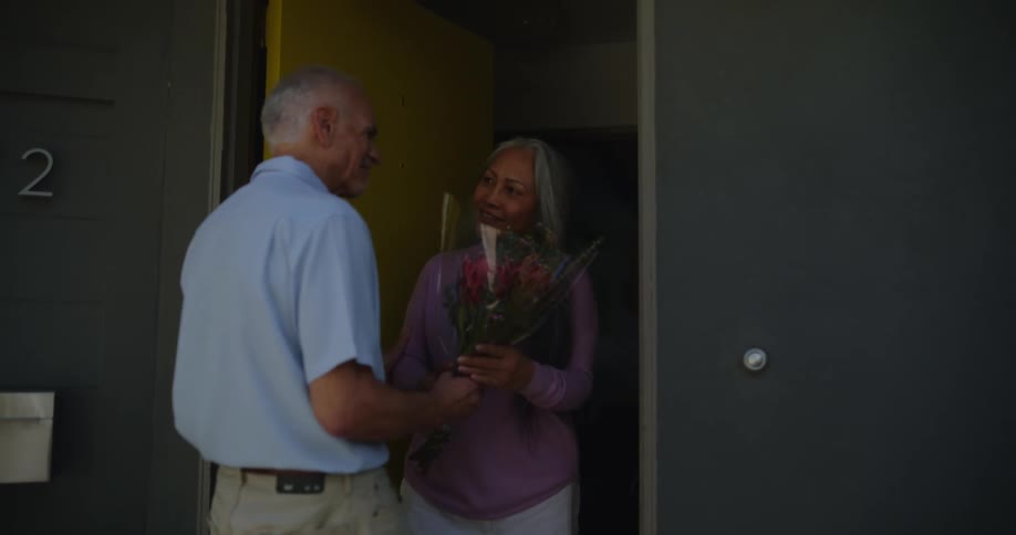 A man gives a woman flowers at her door