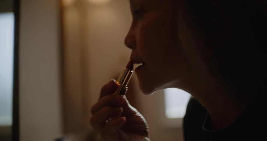 A woman applies lipstick to her lips