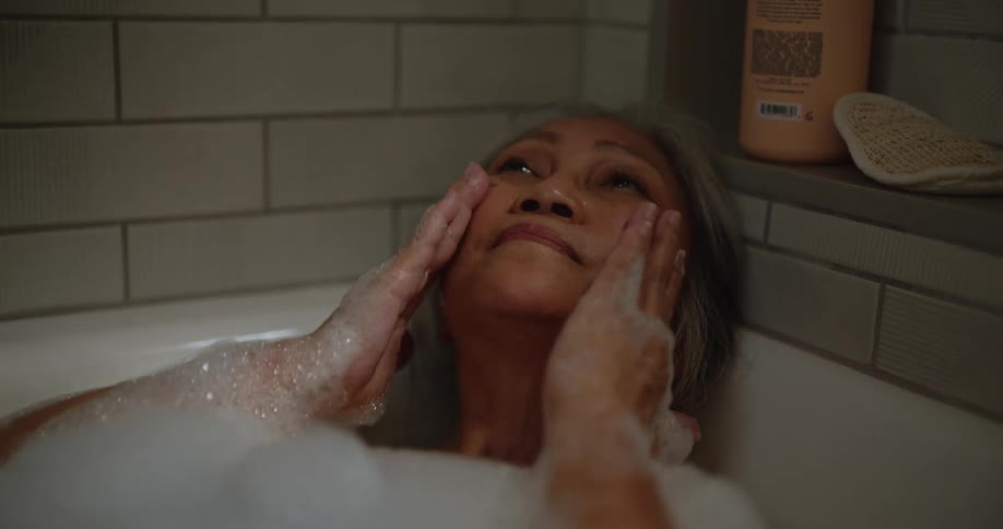 Elderly woman is taking a bath and washing her face