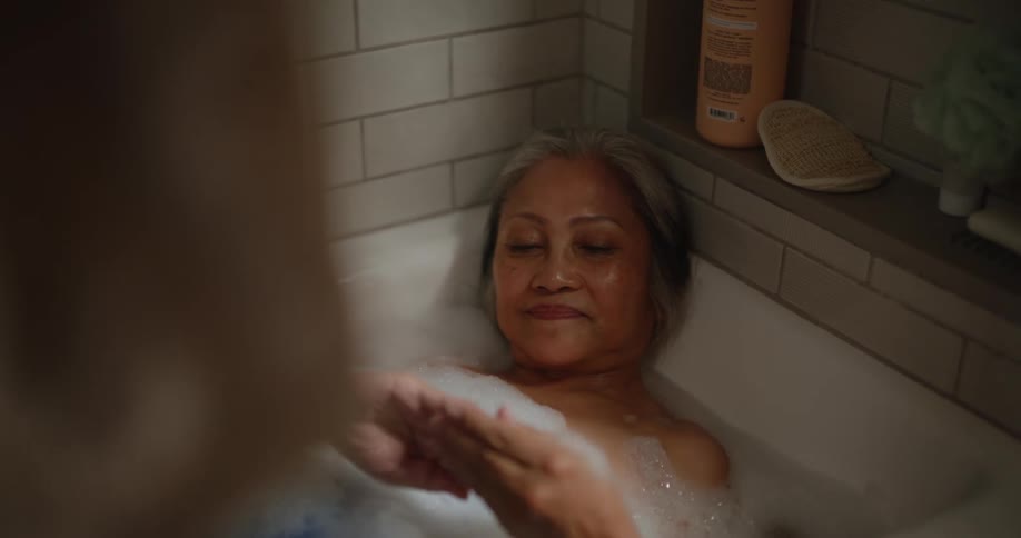 An elderly woman being happy in a bathtub