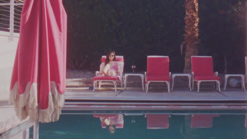 Woman resting on a chair in front of the pool caught on vintage film