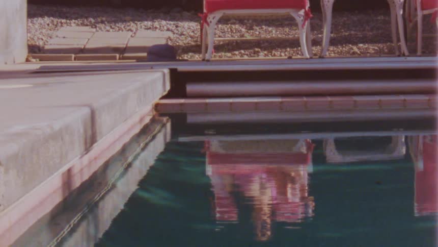 A reflection of a woman relaxing poolside while drinking