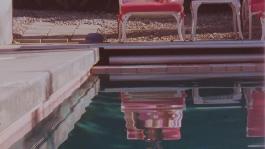 The chairs reflect in the pool water