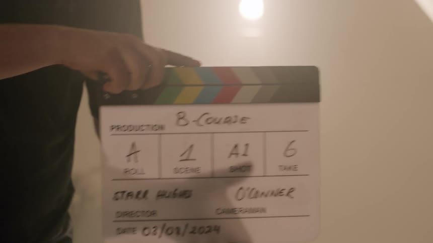 A man is holding a clapperboard in a dimly lit room