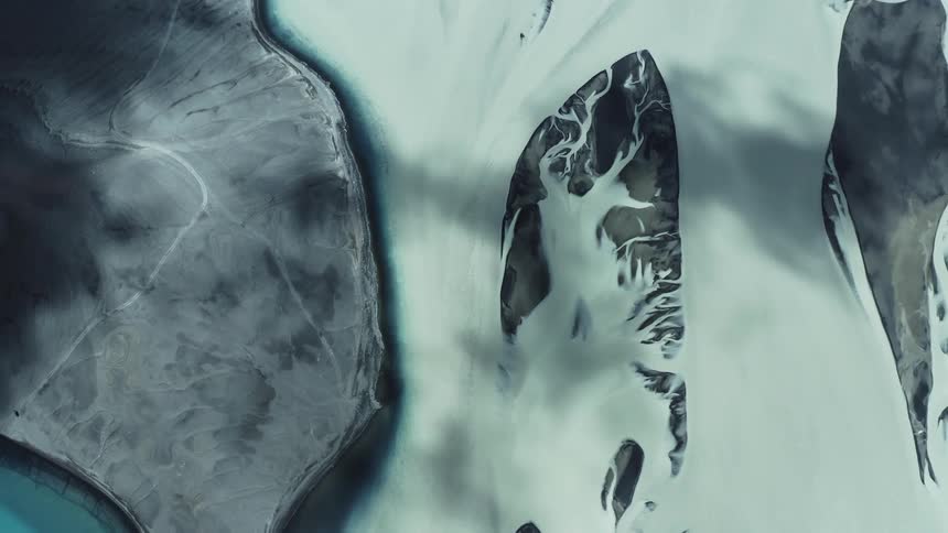 Shadows from clouds move across snow covered terrain near the coast