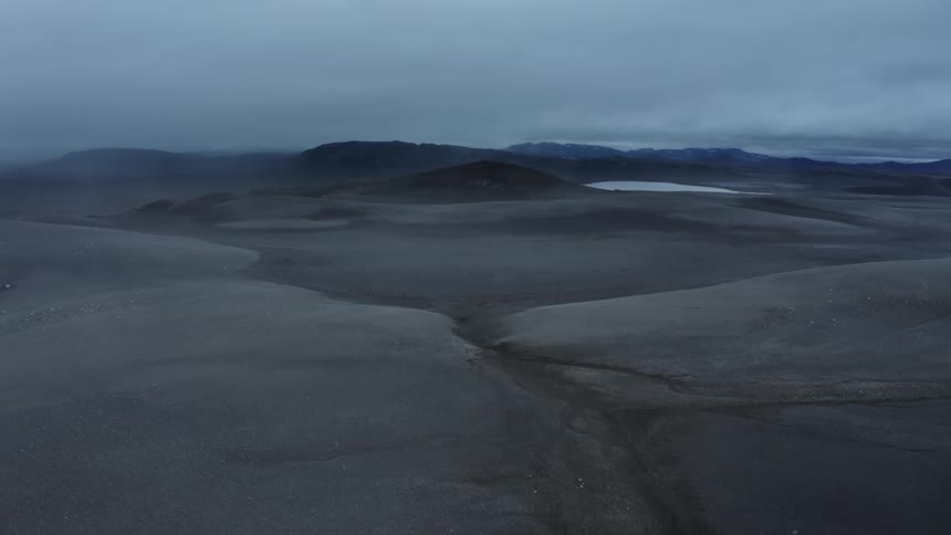 A vast plain stretches to distant mountains and a lake