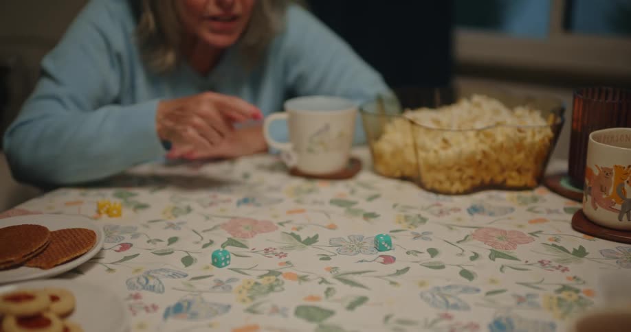 Friends sitting at a table with cups and popcorn playing dice