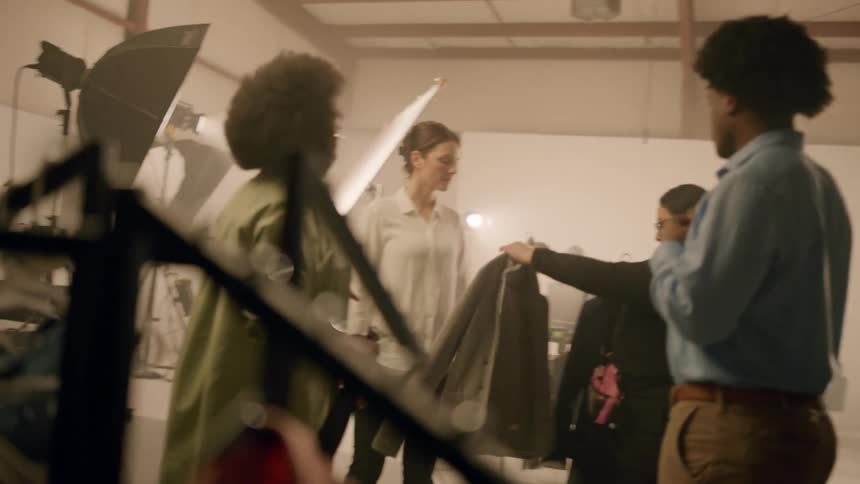 Women and men inside a recording studio putting on clothes and talking