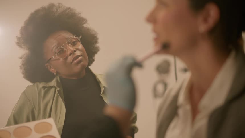 A white women getting make up applied gets snippy with a black woman