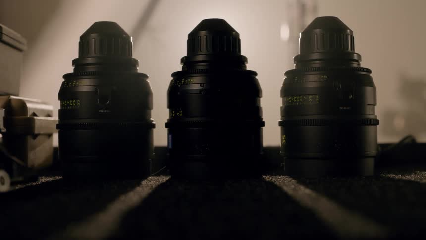 Three professional camera lenses on a studio bench