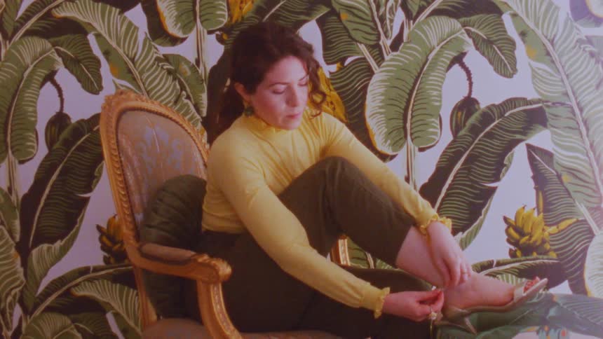 A woman is sitting on a chair putting on high heel sandals