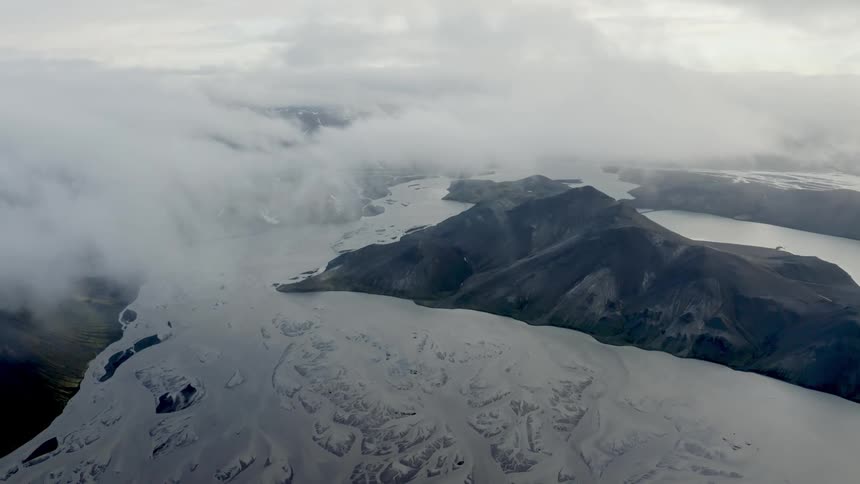 Aerial panorama of mountain ranges with snowcovered lakes on a cloudy day