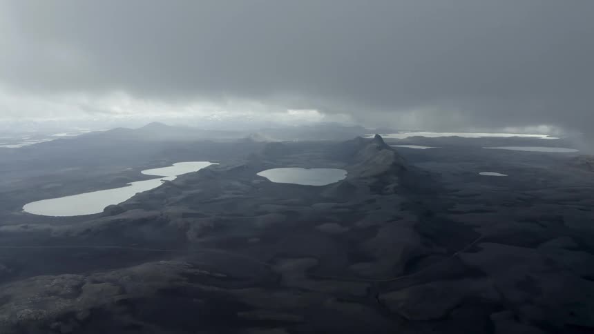 Heavy clouds fill the sky over the lakes in rough gray terrain