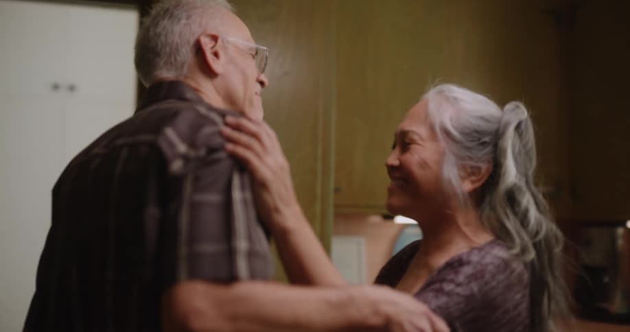 An older couple laughs and dances together in their kitchen