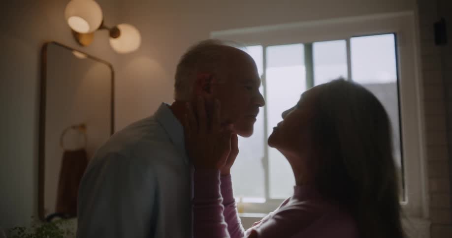 Woman massaging her husbands face and then kissing him while hes in the bathroom