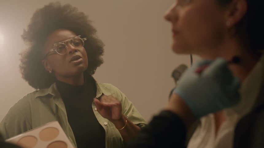A clip of a female making up in the studio while having a chat with a friend