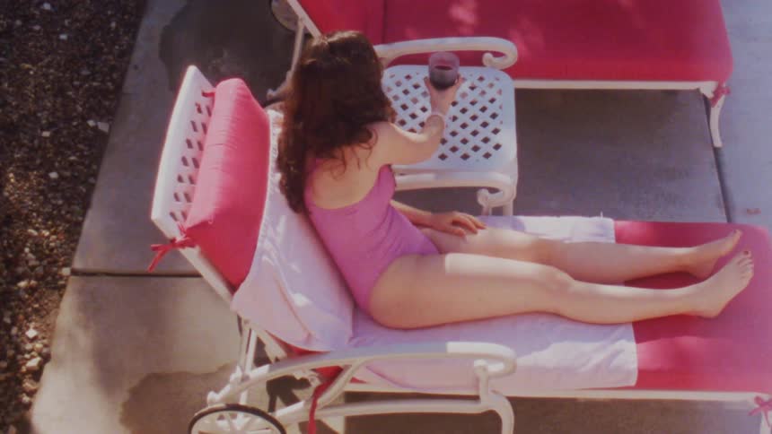 Woman lying down on a chair outdoors enjoying the sun and a drink