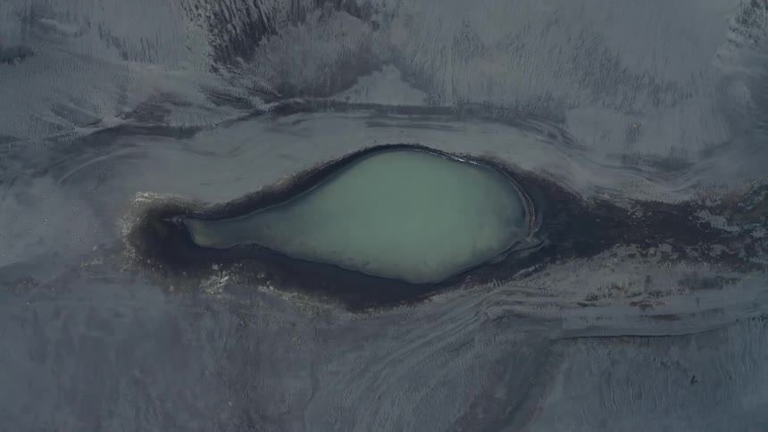 An aerial view of a pond in the middle of a mountain
