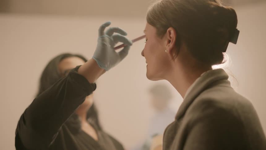 A makeup artist applying makeup to a model in a studio