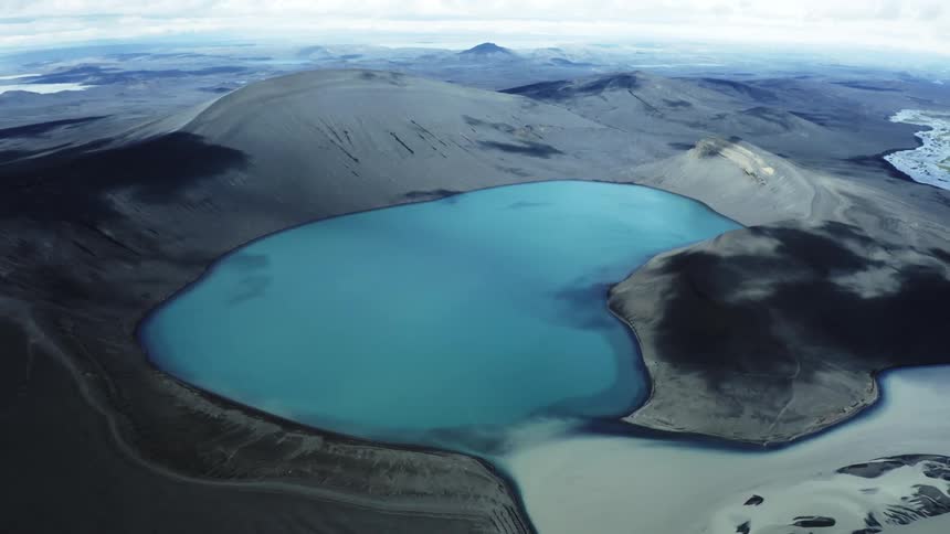 Body of water surrounded by mountains on a cloudy day