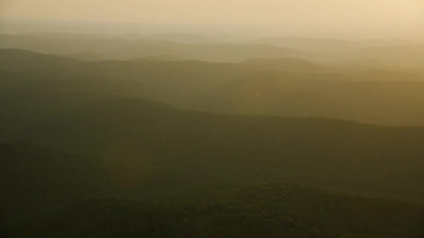 Aerial landscape of mountains with vegetation and morning solar flare