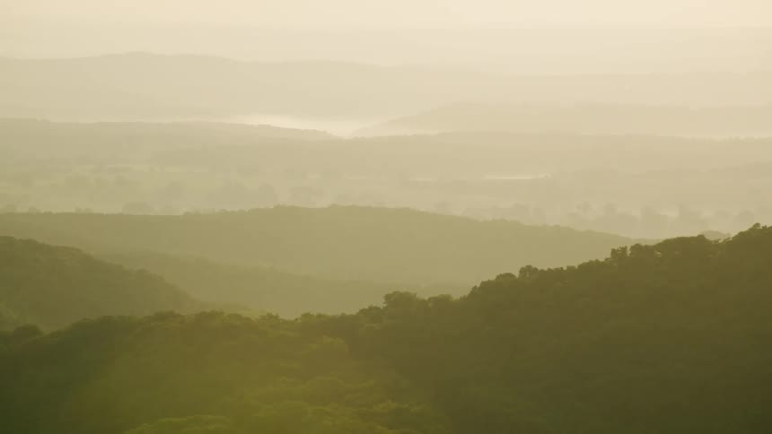 Aerial panorama of mountain ranges covered with forests on a sunny morning
