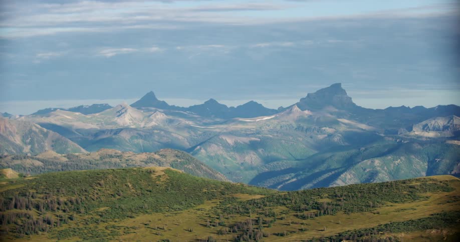 Aerial landscape of hills and mountains and greenish forests on a blue sky day with clouds