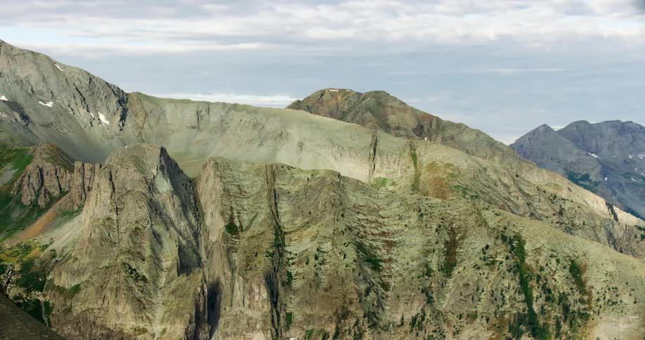 Mountain ridge with jagged peaks lightly covered by moss and black and brown rock