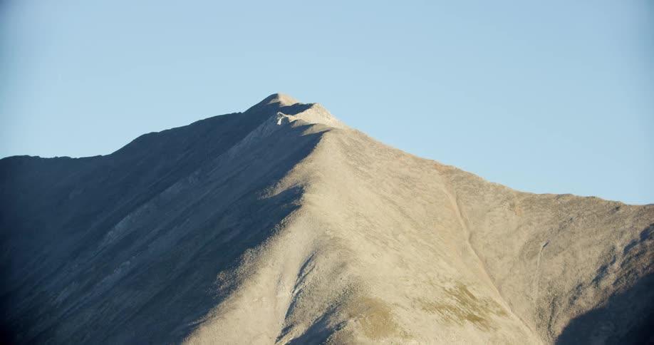 Peak of a barren mountain under a blue sky