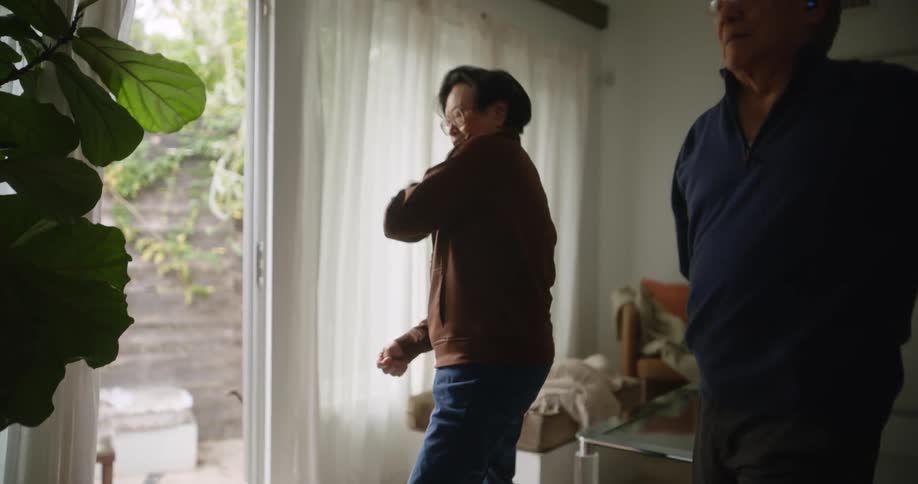 Elderly couple inside a room stretching their body with taichi movements