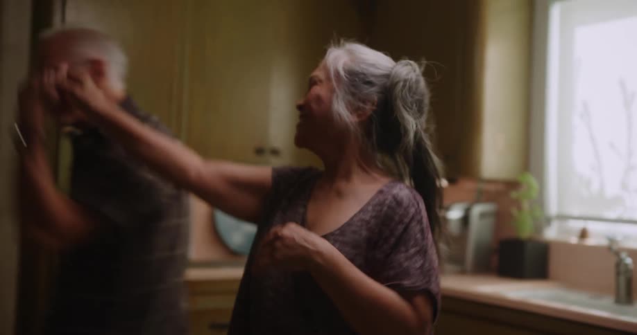 A happy elderly couple dancing in the kitchen at home