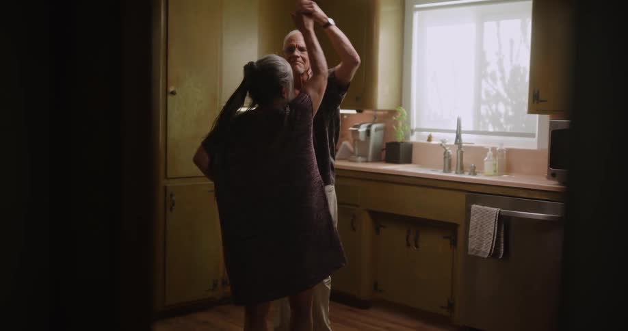 Elderly couple dancing in the kitchen romantically and kissing