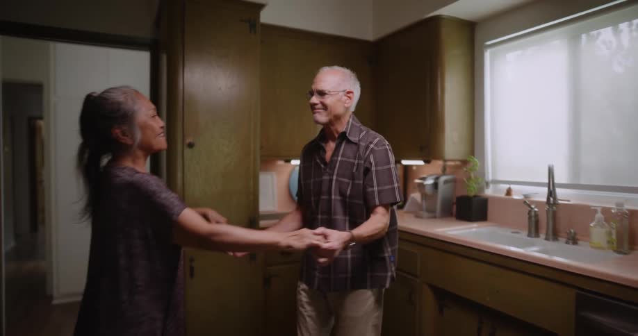 A happy elderly couple dancing on the kitchen at home