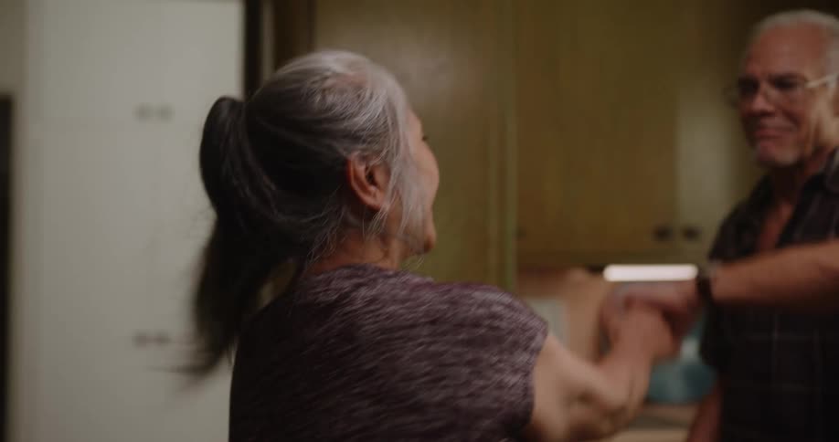 A man and a woman enjoy dancing in a kitchen
