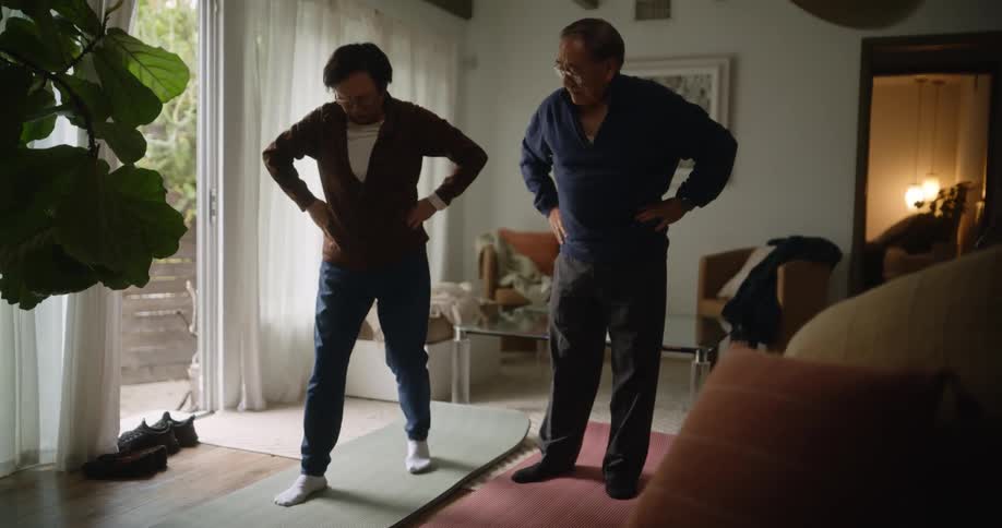 An asian couple exercise together in a living room